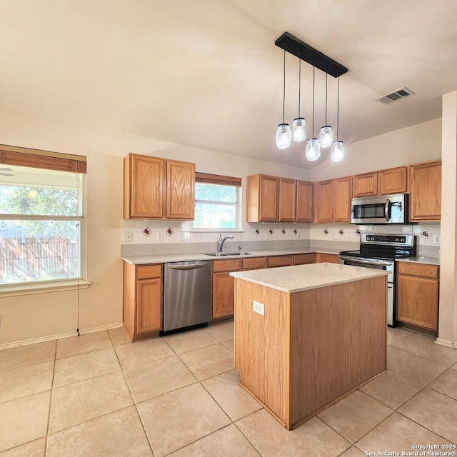 kitchen with light countertops, a center island, appliances with stainless steel finishes, and a sink