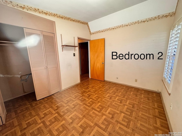 unfurnished bedroom featuring a closet, lofted ceiling, and baseboards