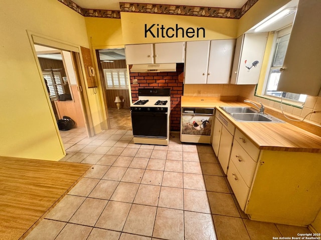 kitchen featuring light tile patterned floors, a sink, gas range oven, under cabinet range hood, and dishwasher