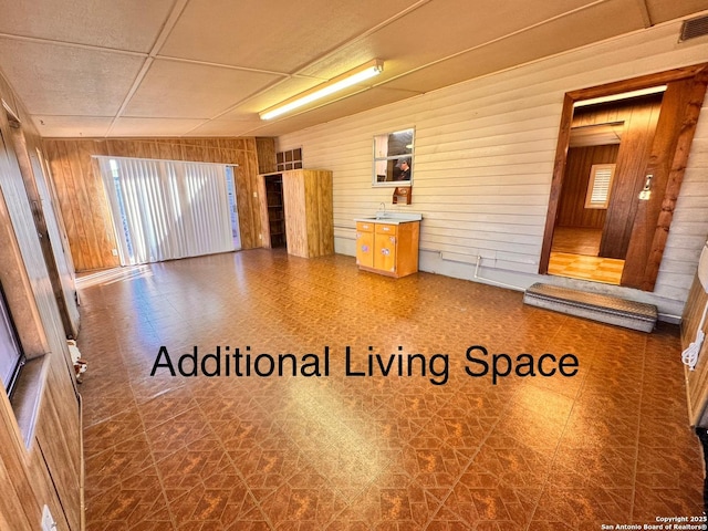 unfurnished room featuring tile patterned floors, a drop ceiling, visible vents, and wood walls