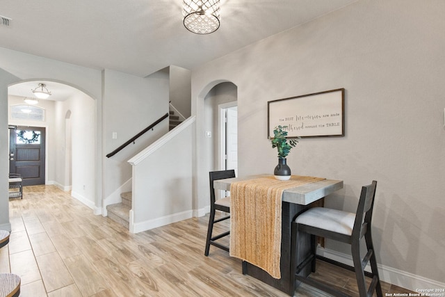 dining space with visible vents, baseboards, stairway, light wood-style flooring, and arched walkways