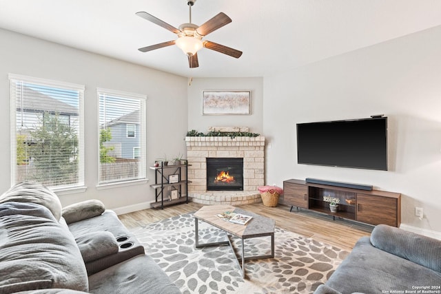 living area with baseboards, a brick fireplace, wood finished floors, and a ceiling fan