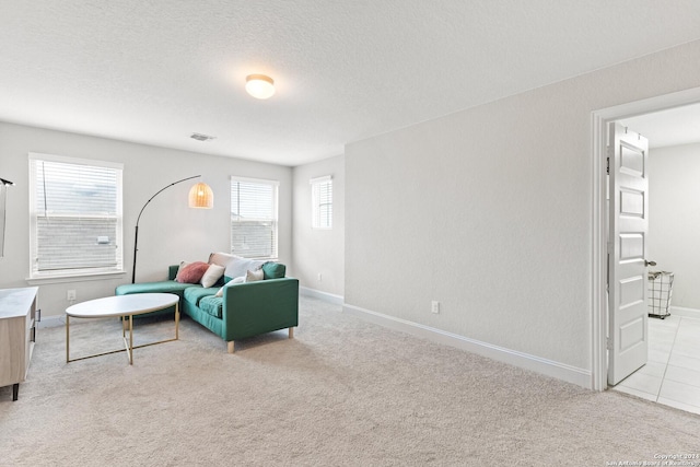 living area with light carpet, a textured ceiling, and baseboards