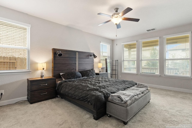 bedroom featuring visible vents, light colored carpet, a ceiling fan, and baseboards