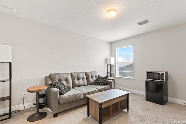 living area with a textured ceiling, baseboards, visible vents, and light carpet