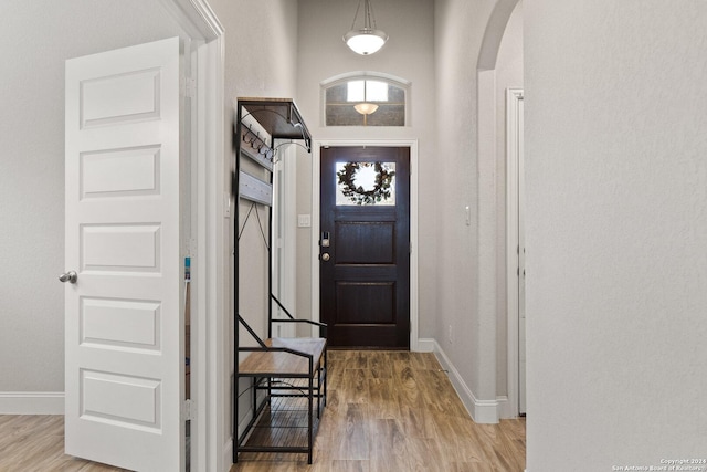 foyer with baseboards, arched walkways, and wood finished floors