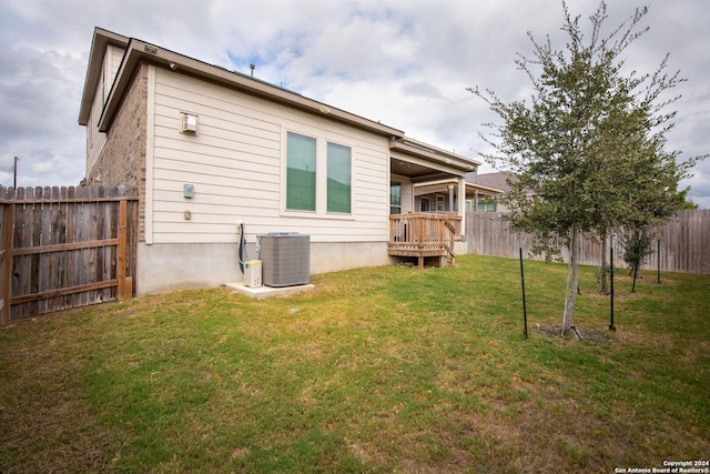 rear view of property featuring a lawn, cooling unit, and a fenced backyard