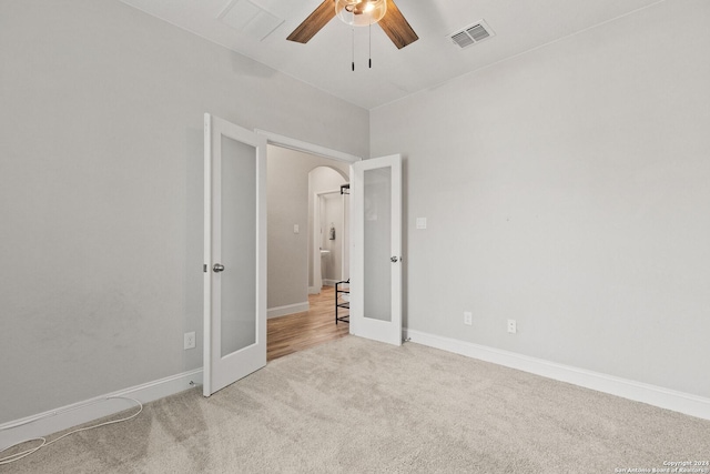 empty room featuring visible vents, a ceiling fan, french doors, arched walkways, and carpet