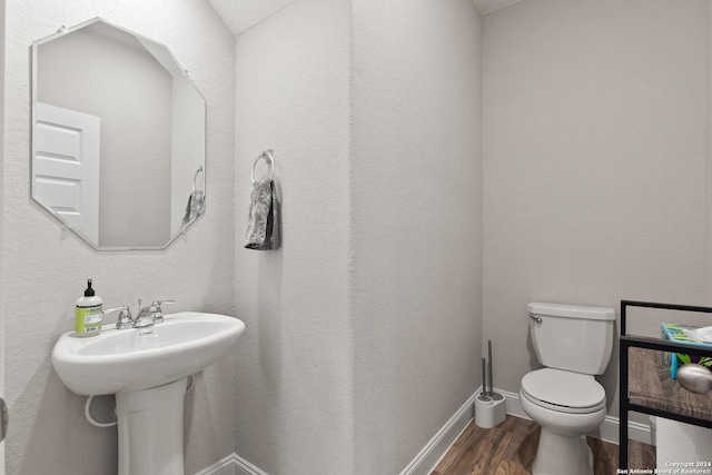 bathroom with toilet, baseboards, and wood finished floors