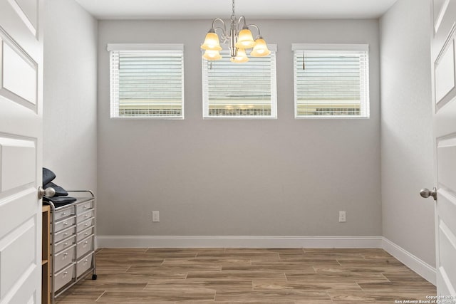 interior space featuring light wood-style flooring, a notable chandelier, and baseboards