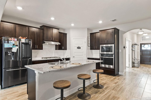 kitchen with visible vents, under cabinet range hood, a sink, stainless steel appliances, and arched walkways