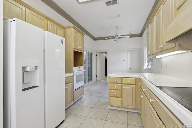 kitchen featuring visible vents, light brown cabinetry, tile countertops, white appliances, and crown molding