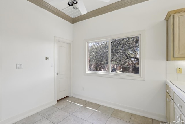 unfurnished dining area with light tile patterned floors, baseboards, ornamental molding, and a ceiling fan