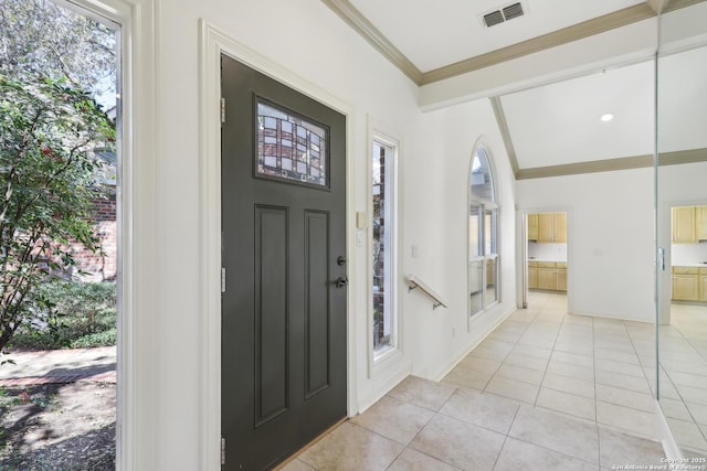 entrance foyer with lofted ceiling, light tile patterned flooring, visible vents, and ornamental molding