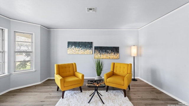 sitting room with wood finished floors, visible vents, and baseboards