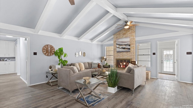 living area featuring baseboards, lofted ceiling with beams, a fireplace, wood finished floors, and a ceiling fan