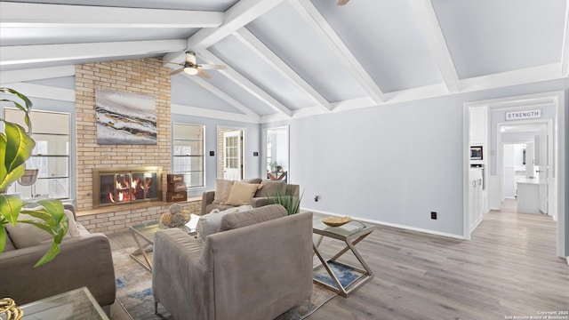 living area with lofted ceiling with beams, plenty of natural light, wood finished floors, and a fireplace