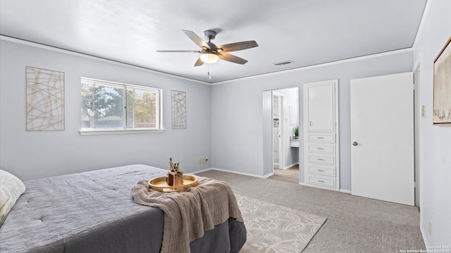 carpeted bedroom featuring visible vents, connected bathroom, baseboards, ornamental molding, and a ceiling fan