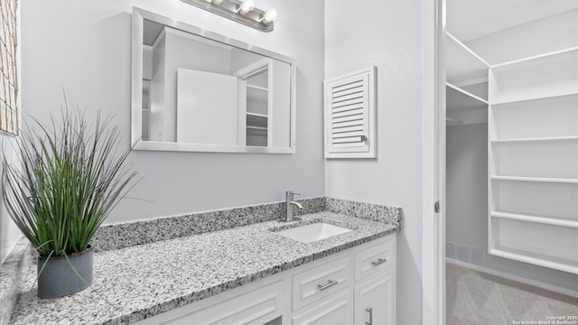 bathroom featuring visible vents, vanity, and a walk in closet