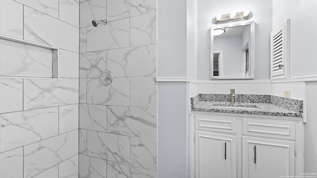 bathroom featuring tiled shower and vanity