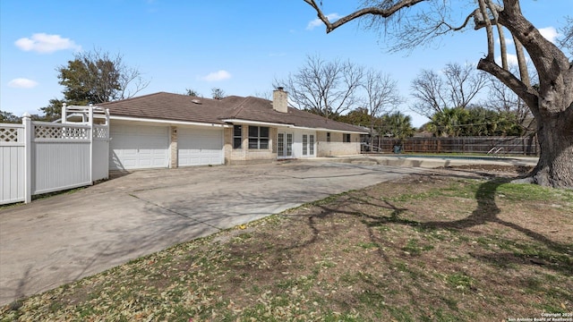 exterior space with fence, a fenced in pool, driveway, an attached garage, and a chimney