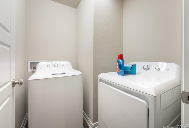 clothes washing area with laundry area, washer and dryer, and a textured wall