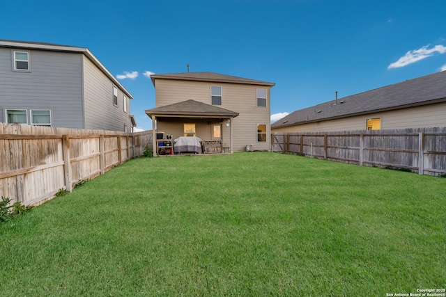 back of house with a yard and a fenced backyard