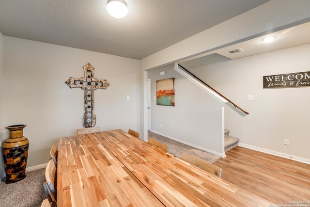 interior space with stairway, baseboards, visible vents, and a textured ceiling