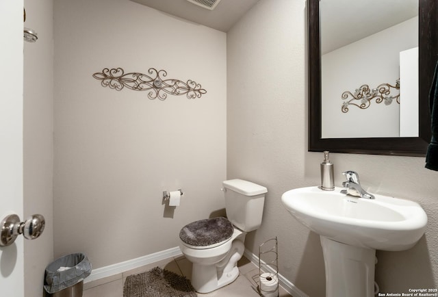 bathroom featuring tile patterned floors, visible vents, toilet, a sink, and baseboards