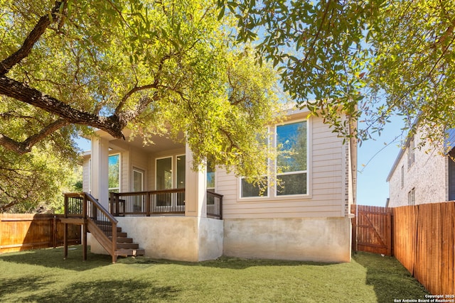 rear view of house featuring a yard, a fenced backyard, and stairs