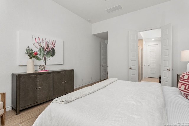 bedroom with visible vents, baseboards, and wood finished floors