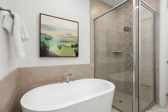 full bath with a shower stall, tile walls, and a freestanding tub