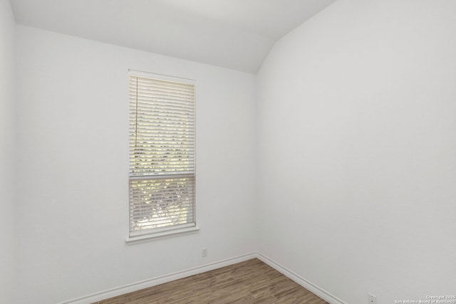 empty room with baseboards, lofted ceiling, and wood finished floors