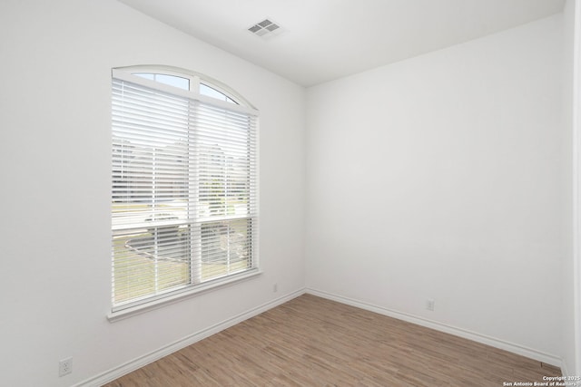 empty room with light wood-type flooring, visible vents, and baseboards