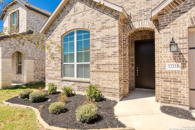 doorway to property with brick siding and a garage