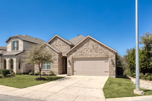 french country style house with a front lawn, an attached garage, brick siding, and driveway