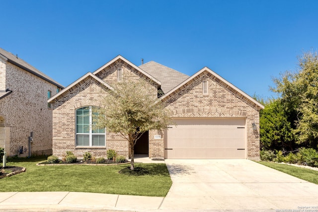 french country style house featuring a front lawn, an attached garage, brick siding, and concrete driveway