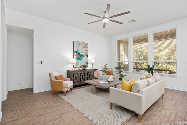 living area with ceiling fan, baseboards, visible vents, and light wood-type flooring