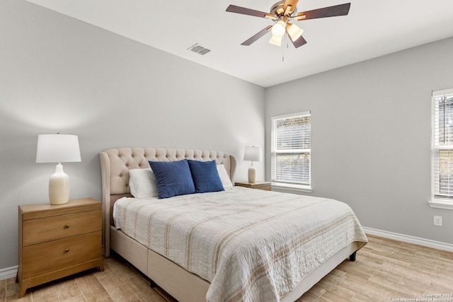 bedroom featuring ceiling fan, light wood-style floors, visible vents, and baseboards