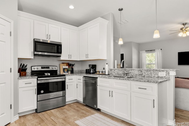 kitchen featuring light wood-style flooring, appliances with stainless steel finishes, a peninsula, white cabinetry, and a sink