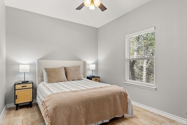 bedroom with light wood-style flooring, a ceiling fan, and baseboards