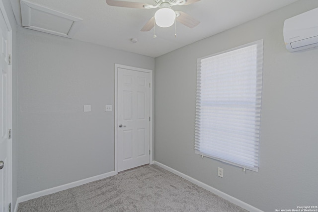 empty room with an AC wall unit, carpet, baseboards, attic access, and ceiling fan