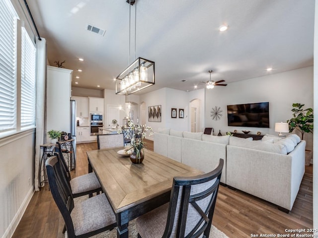 dining space with wood finished floors, recessed lighting, visible vents, and arched walkways