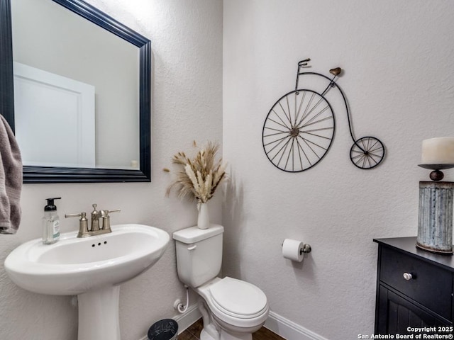 half bath with toilet, baseboards, and a textured wall