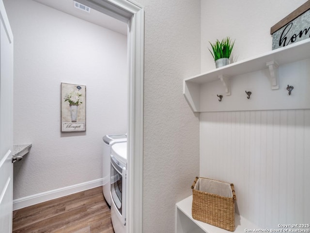 laundry area featuring visible vents, washer and clothes dryer, wood finished floors, baseboards, and laundry area