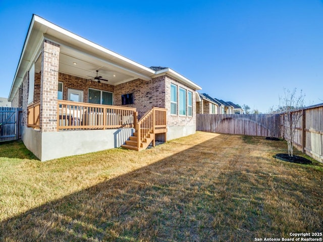 rear view of house featuring a yard, brick siding, a fenced backyard, and a ceiling fan