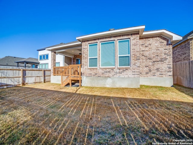 rear view of house with brick siding, fence private yard, and a yard