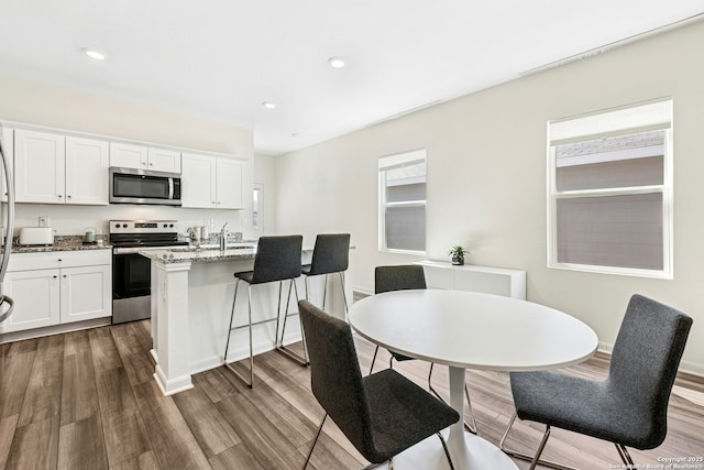 kitchen featuring stainless steel appliances, light stone countertops, dark wood-type flooring, and white cabinetry