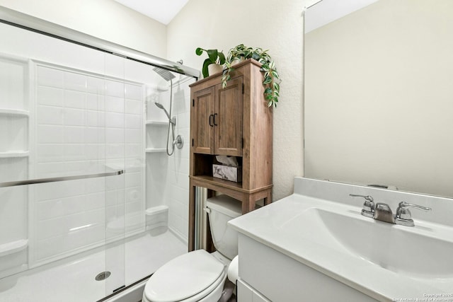 bathroom featuring vanity, toilet, a textured wall, and a stall shower