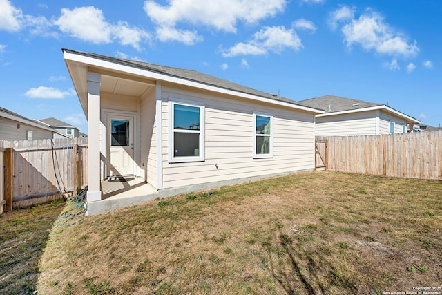 back of house with a lawn and a fenced backyard